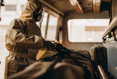 Person wearing protective hazmat suit and mask preparing equipment inside a vehicle during biohazard cleanup