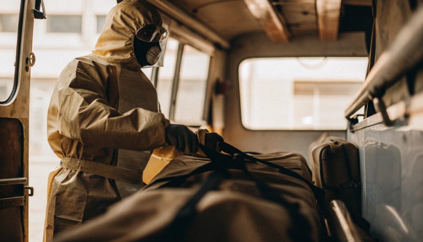 Person wearing protective hazmat suit and mask preparing equipment inside a vehicle during biohazard cleanup