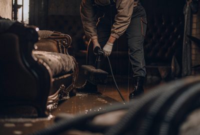 Professional performing water mitigation by extracting standing water from flooded living room