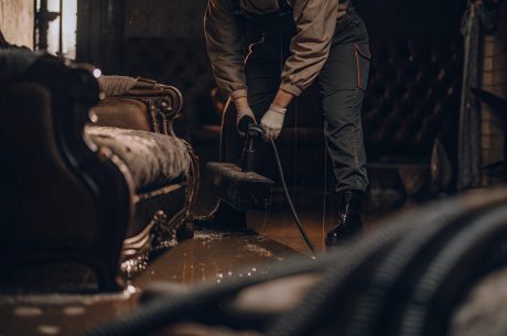 Professional performing water mitigation by extracting standing water from flooded living room