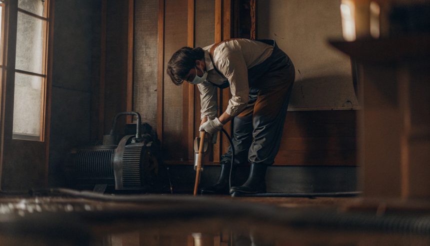 Professional inspecting and removing water from a flooded home in Alexandria, highlighting hidden water damage restoration costs.