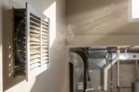 Dust and airborne particles blowing from an HVAC air vent, illustrating how mold spores can circulate through indoor air systems
