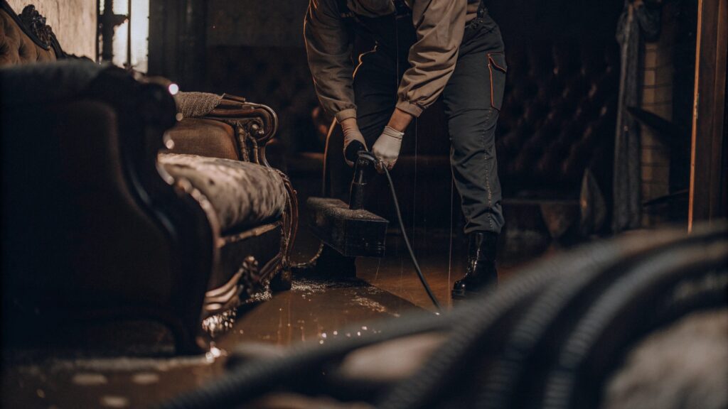 Professional performing water mitigation by extracting standing water from flooded living room