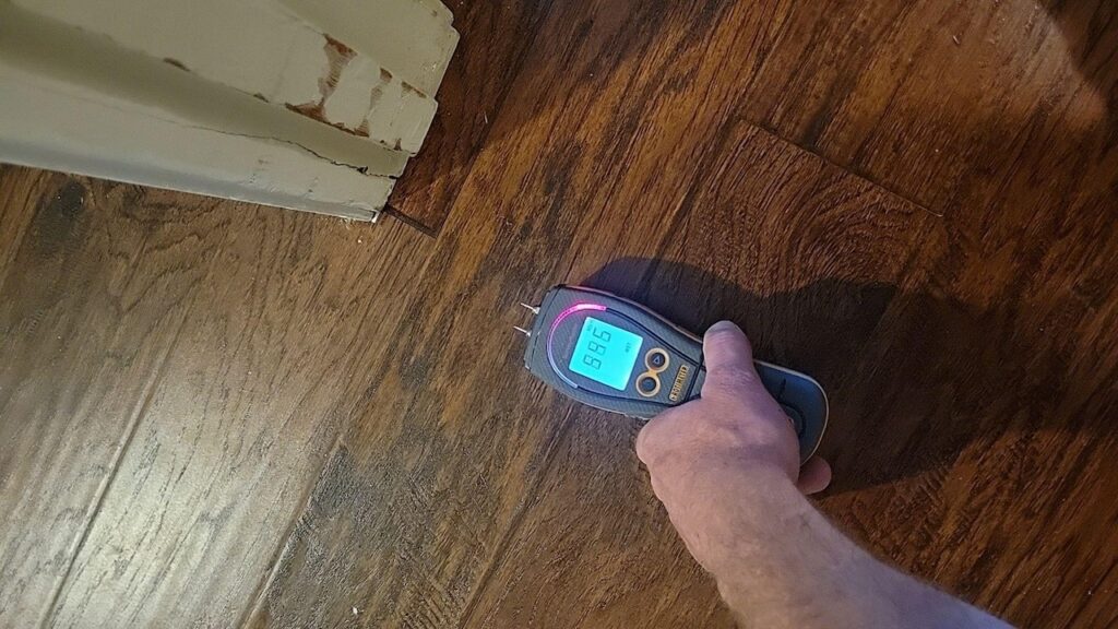 A moisture meter detecting wet damage on vinyl flooring.