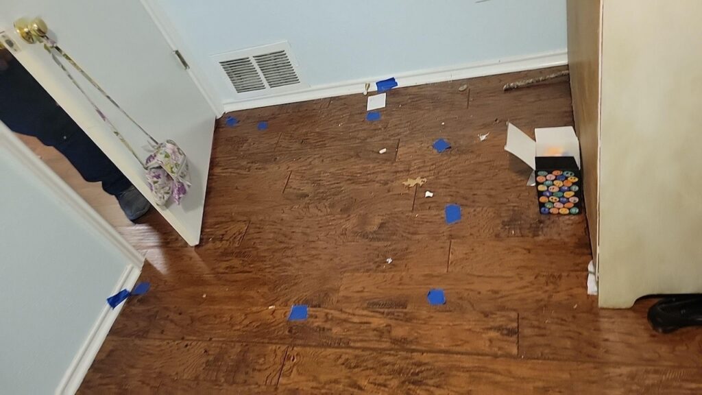 Laminate floor water damage marked with duct tape.