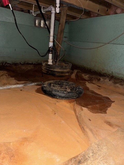 The area surrounding a sump pump in a crawlspace is affected by mold.