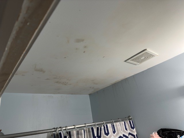 A bathroom ceiling has evidence of mold growth due to poor ventilation.