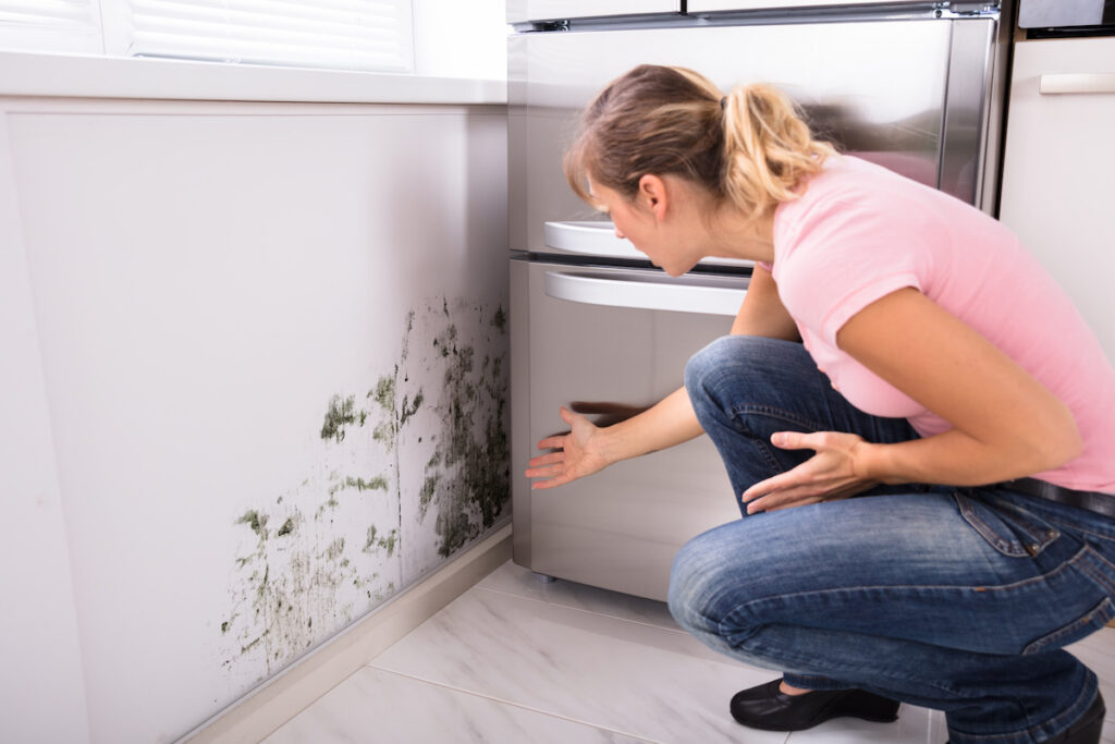 A woman reacting to the presence of mold in her kitchen