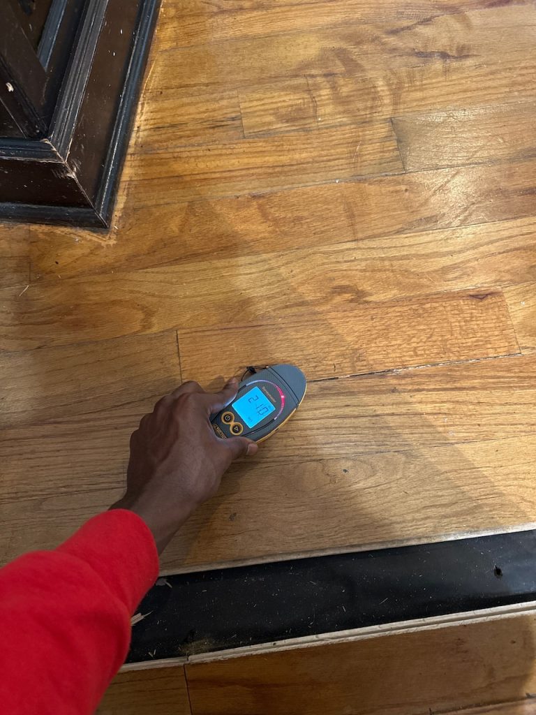 A moisture meter is used on vinyl wooden flooring.