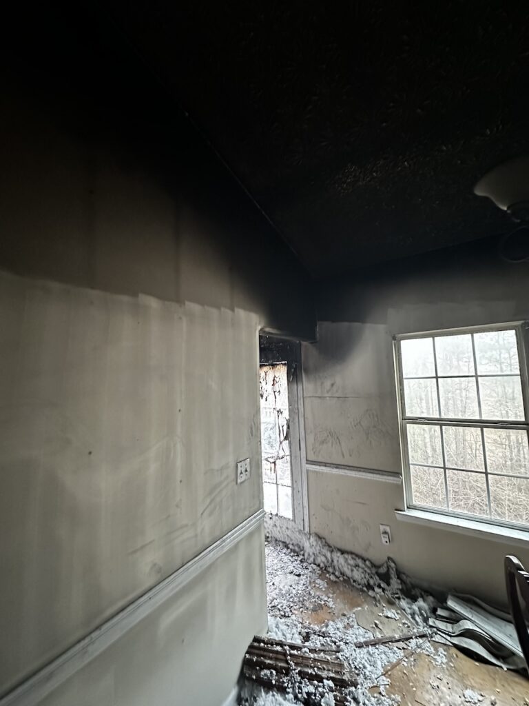 A charred interior of a home after a grease fire, with blackened walls and debris on the floor.