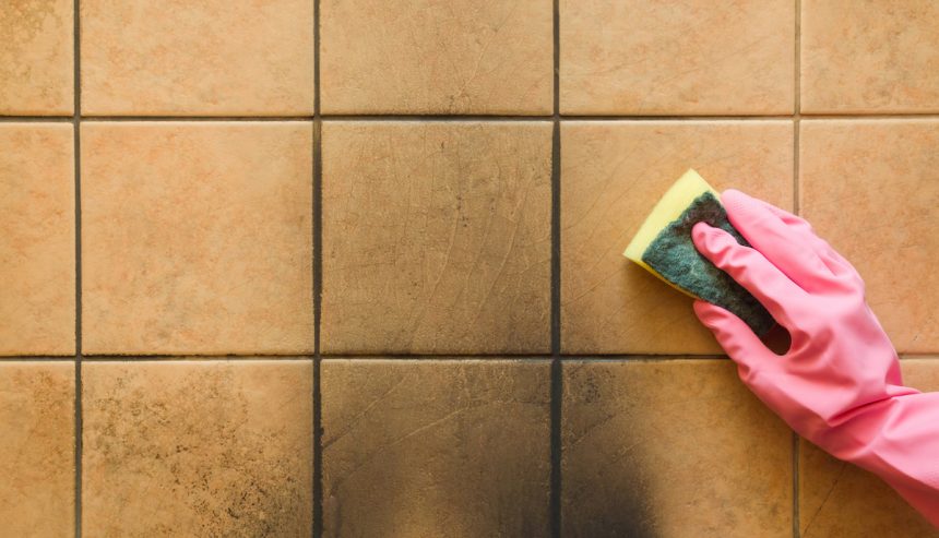 Employee hand in rubber protective glove with sponge washing the black soot marks from furnace on tiles wall. Early spring general or regular cleanup. Commercial cleaning company. Service concept.