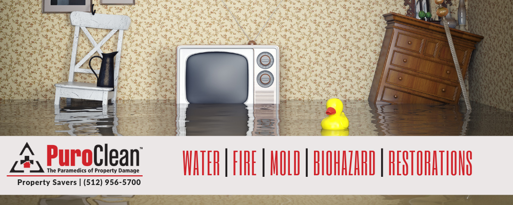 Flooded room with a vintage TV, a rubber duck, and water-damaged furniture, highlighting water damage issues.