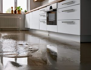Standing water on a kitchen floor and cabinet bases, showing what may need to be replaced after water damage