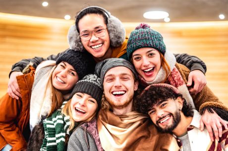 Happy multiracial guys and girls taking selfie in warm fashion clothes. Winter safety tips.