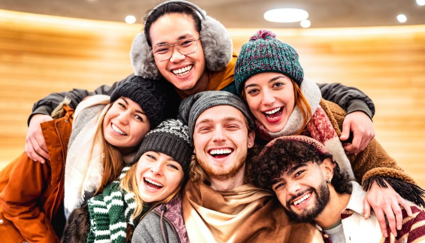 Happy multiracial guys and girls taking selfie in warm fashion clothes. Winter safety tips.