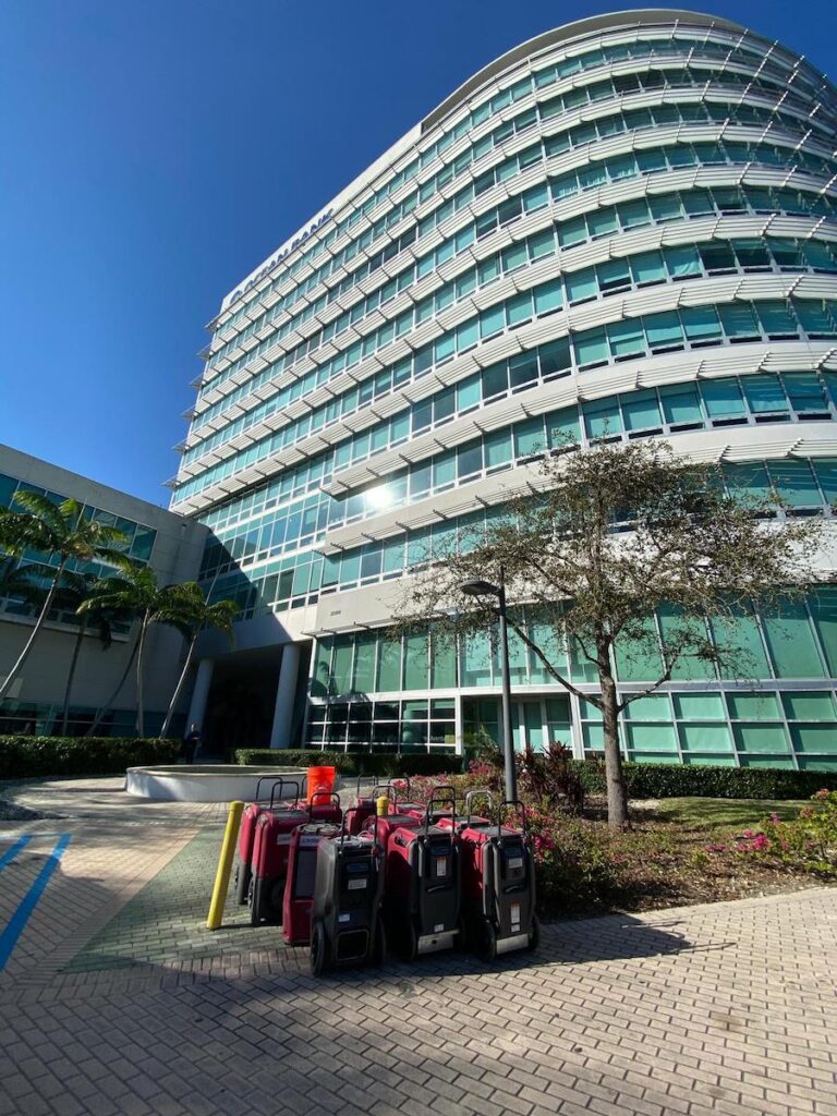 Water restoration equipment lined up outside a modern glass building under a clear blue sky.