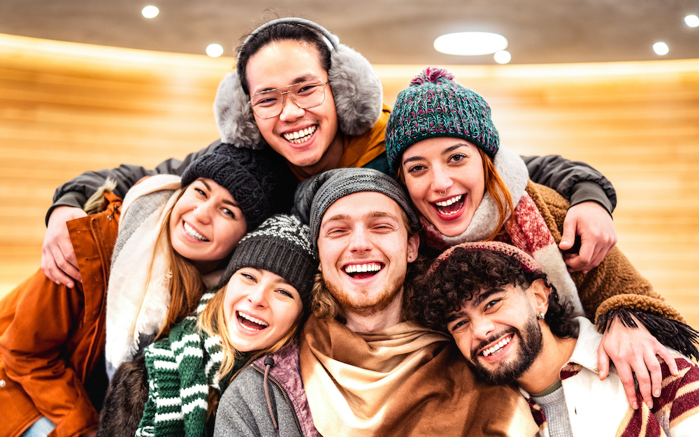 Happy multiracial guys and girls taking selfie in warm fashion clothes. Winter safety tips.