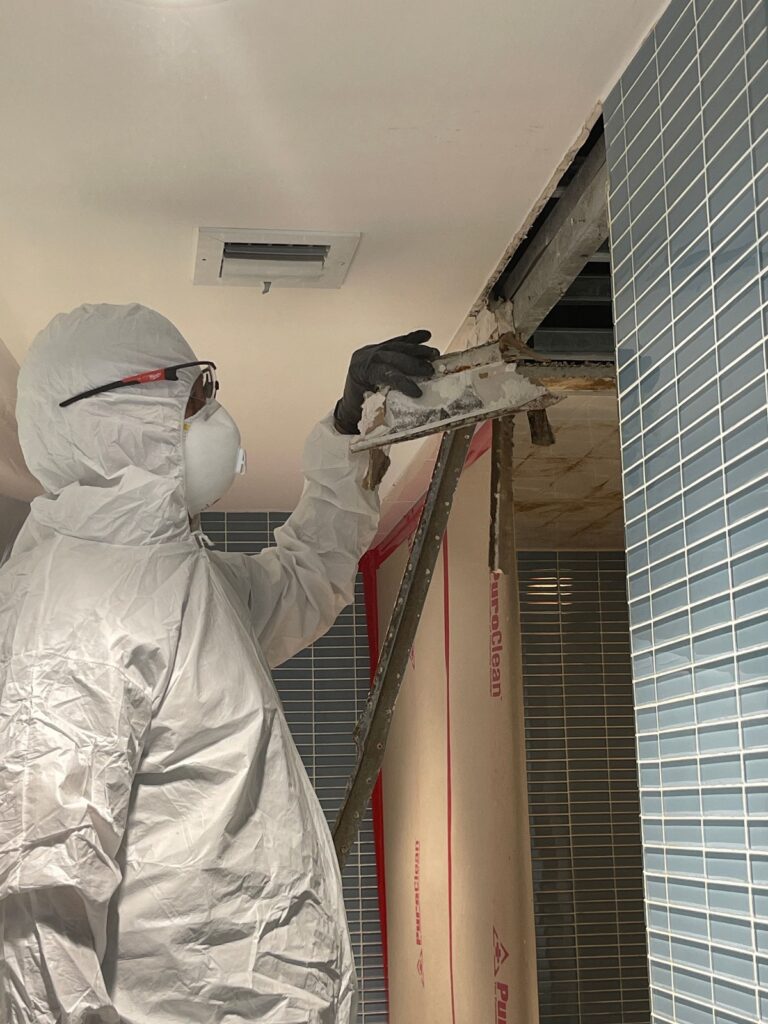 Technician inspecting bathroom ceiling mold.