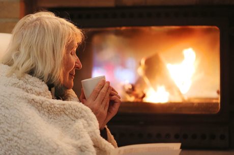 Senior woman relaxing by fireplace