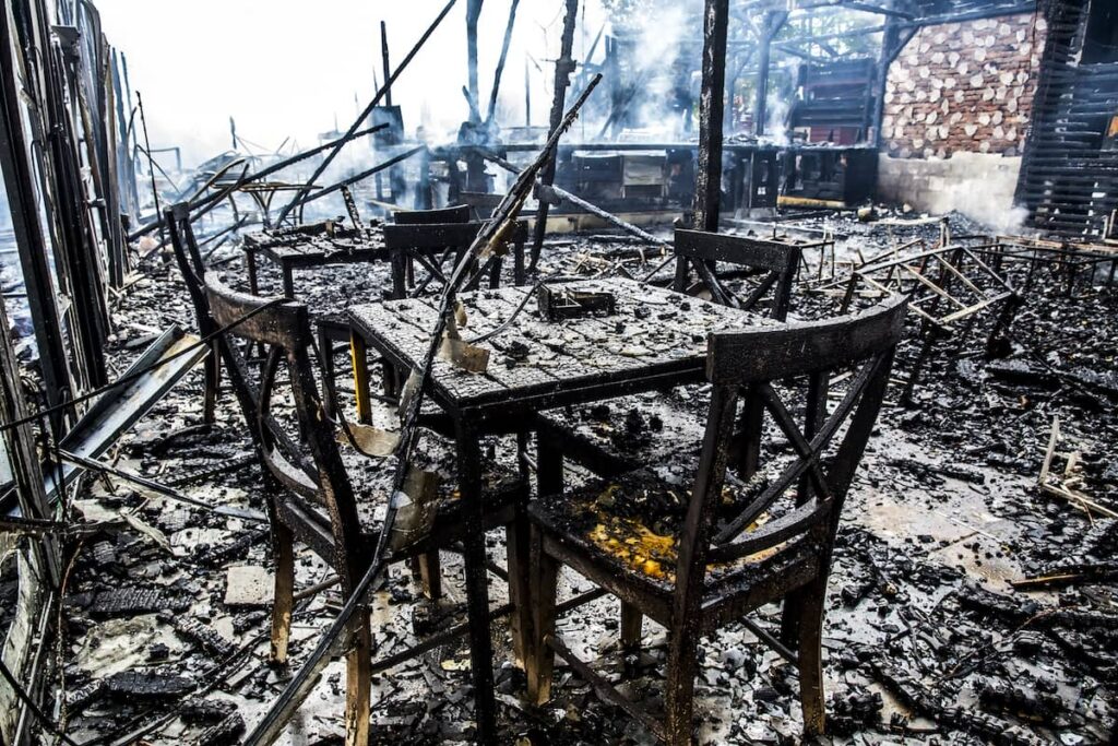 Charred furniture and debris in a smoke-damaged interior, illustrating the aftermath of a fire.