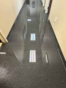 A long hallway with a dark textured floor is completely covered in reflective standing water.