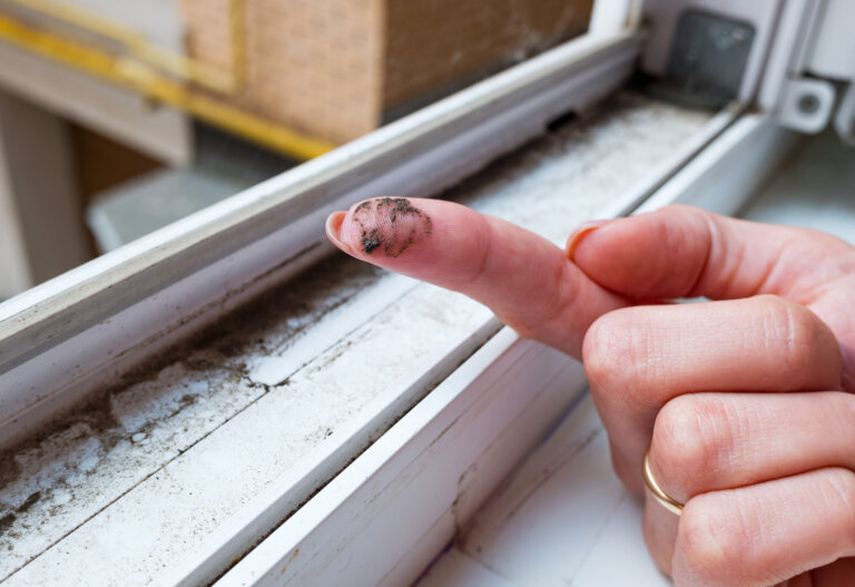 A dirty finger highlights the accumulated dust and grime on a neglected window sill.