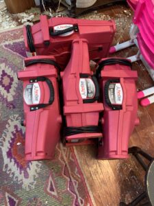 Three red PuroClean Velo Pro airmovers are positioned on a debris-covered floor