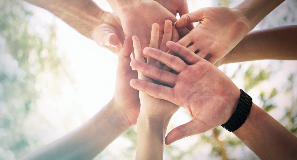 team of people bringing their hands together