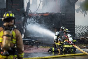 firefighters spraying water to put out a house fire