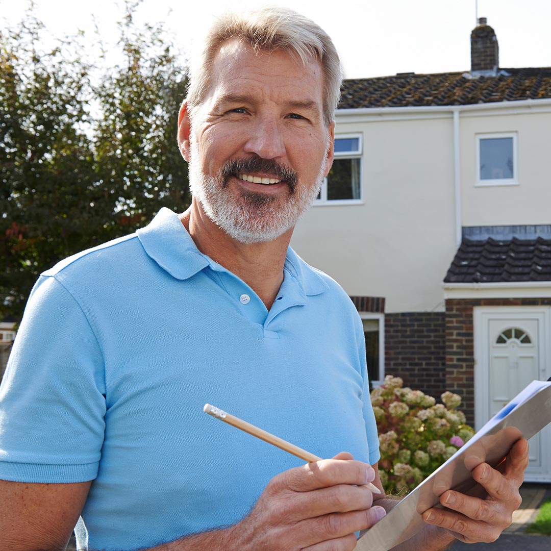 smiling man filling out paperwork outside of a home