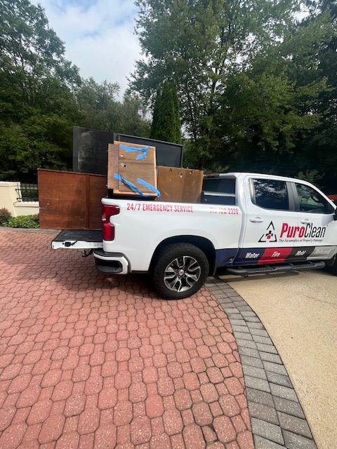 PuroClean truck removing water-damaged furniture and debris after basement flood in Roswell, GA