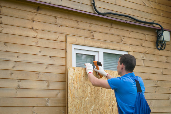 A man boarding up windows to protect his home from tornado damage.