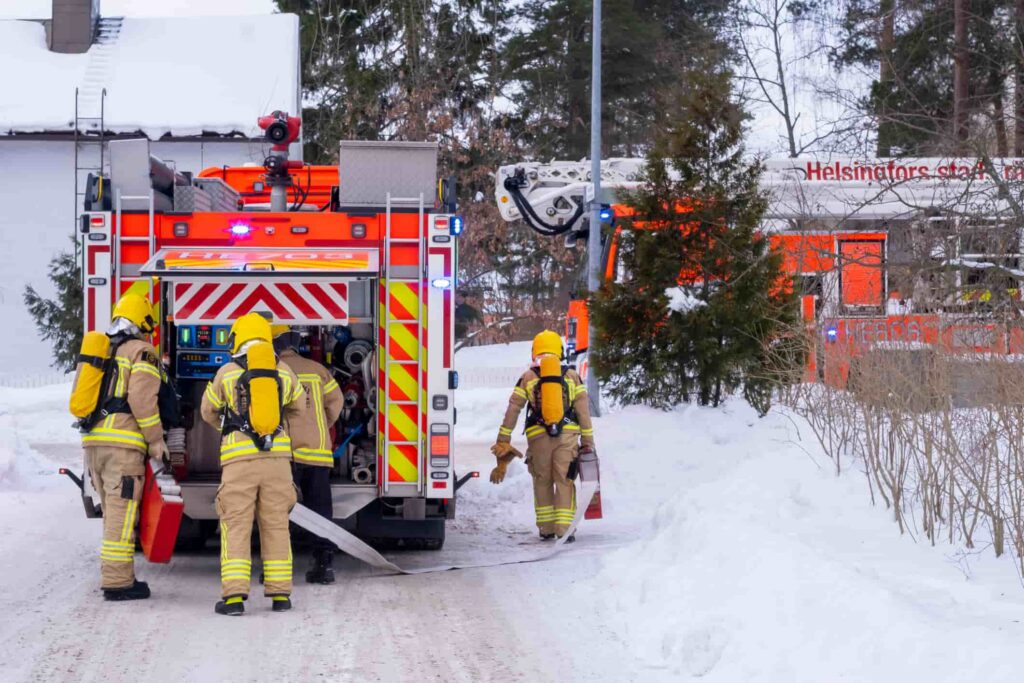 Firefighters working beside fire trucks in snowy conditions, illustrating hazardous cold weather across Metro Atlanta.