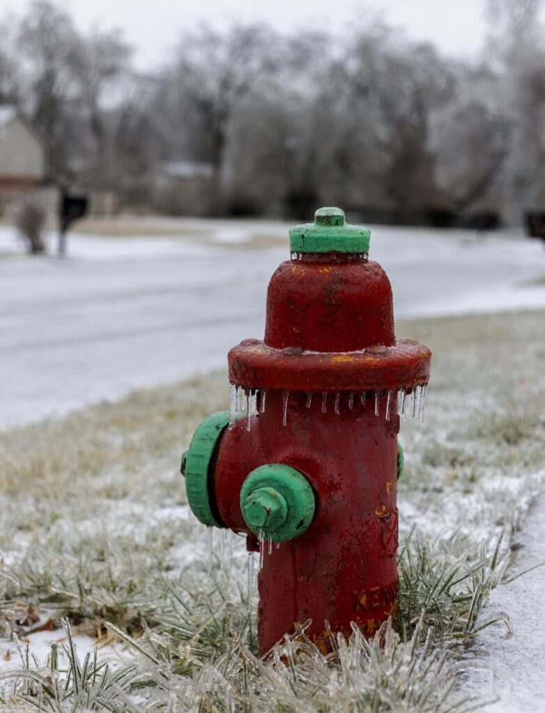 Frozen red fire hydrant covered in icicles during Georgia winter freeze, showing the importance of pipe protection.
