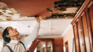 Professional inspecting ceiling for hidden water damage inside home