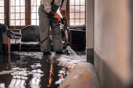 Worker extracting water from a flooded home interior