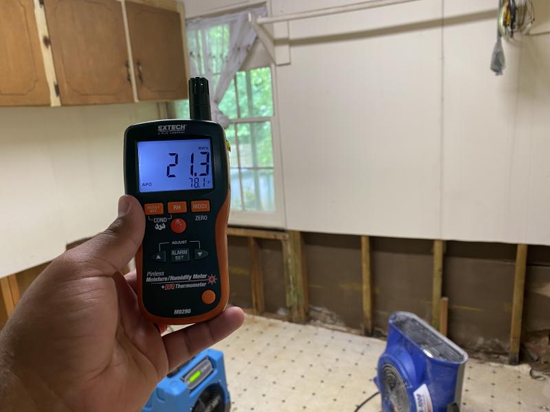 Technician using moisture meters on flooring wet from firefighting water
