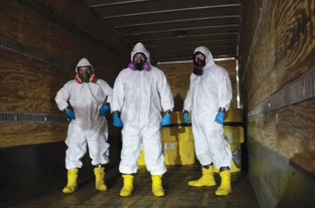Technician in full protective gear preparing equipment outside a Centennial property