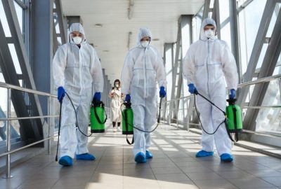 professional biohazard cleanup technician in full PPE performing sanitization