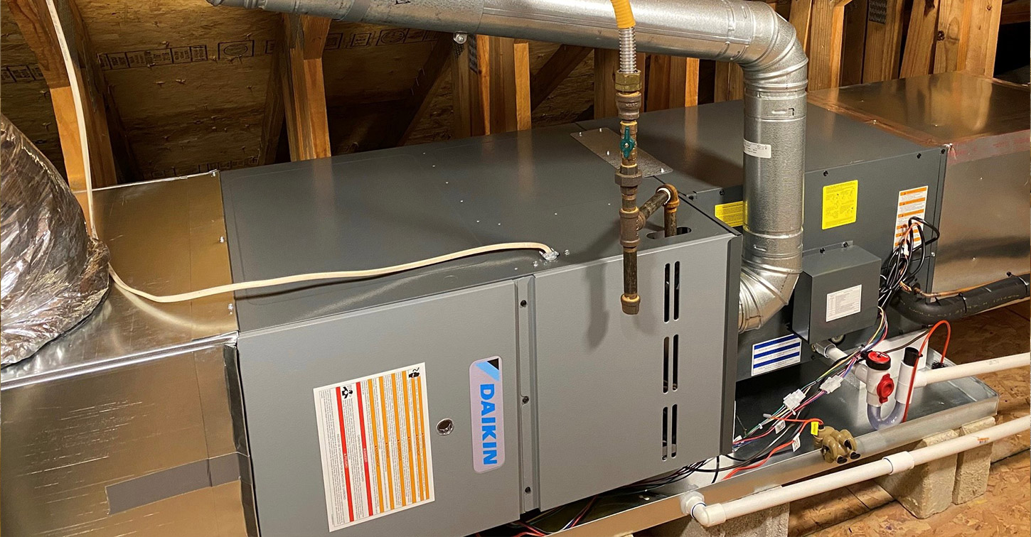 A grey Daikin HVAC air handler unit with metal ductwork and pipes is installed in