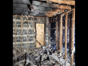Severe structural fire damage in a Chicago building showing exposed framing, burned joists, and fire-damaged debris on the floor.