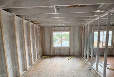 Interior view of a residential reconstruction project with exposed framing and subflooring during the early stages of code compliant reconstruction. Proper structural upgrades and layout adjustments are underway to meet local building codes and safety regulations.