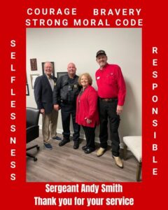 Four individuals pose together in a room, celebrating Sergeant Andy Smith as the SuperHero of the Month for November.