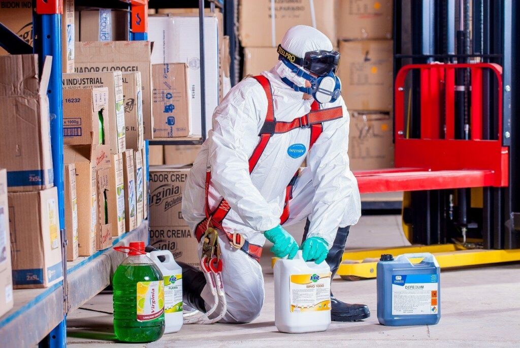 Technician wearing protective gear disinfecting office equipment and furniture