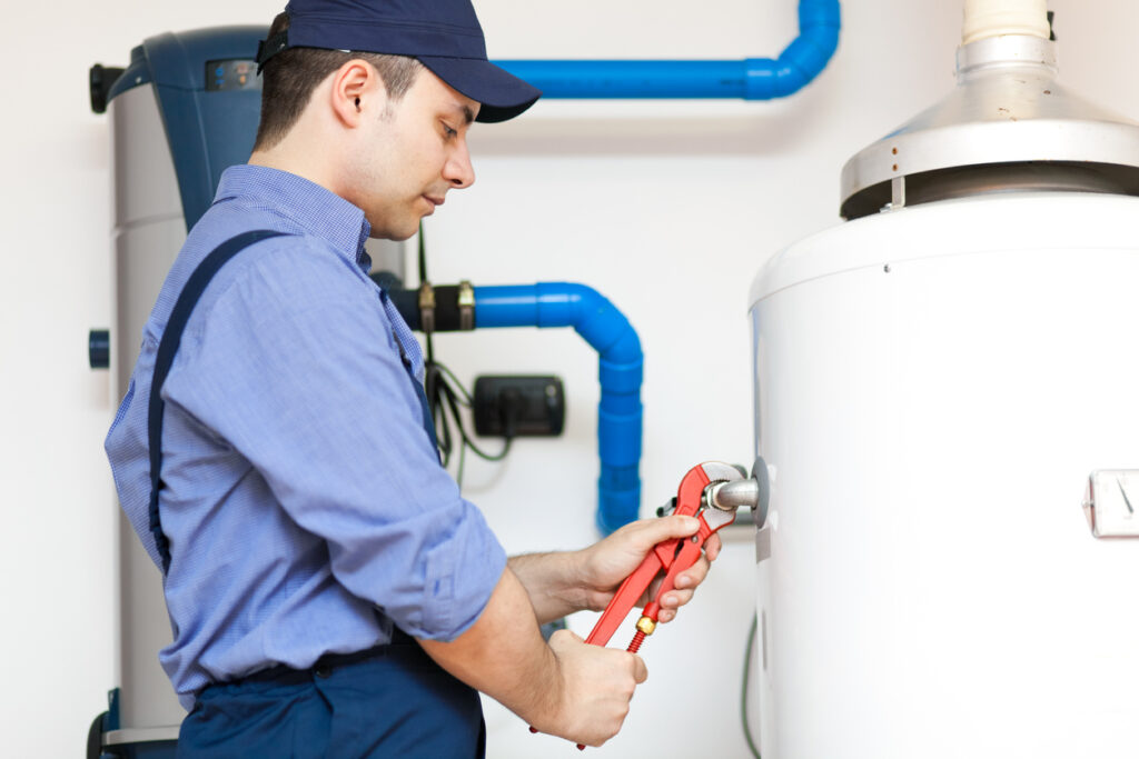 Homeowner checking water heater connections and plumbing pipes for leaks
