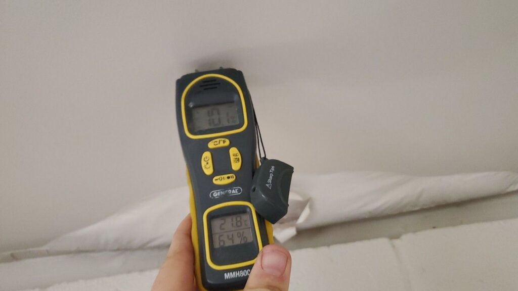 technician using a moisture probe to check for dampness behind a kitchen cabinet