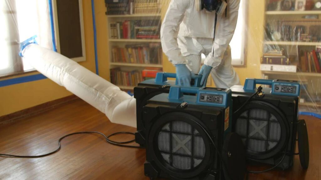 restoration technician setting up a HEPA air filtration system for mold removal