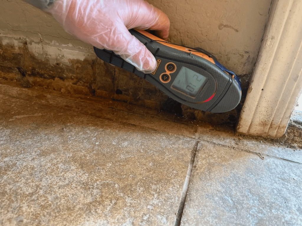 technician checking the moisture levels of wooden floor joists after a flood