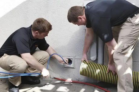 Technician inspecting and cleaning HVAC duct using a vacuum hose