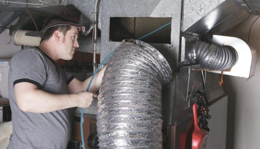 Technician inspecting ductwork inside a Covington home with HVAC panels removed